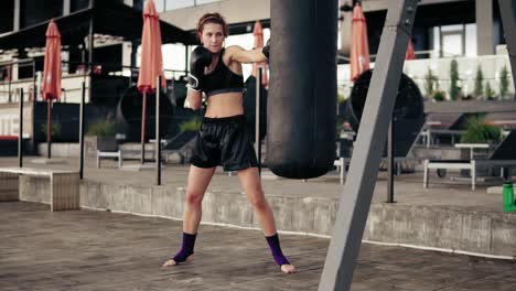 Female-boxer-exercising-outdoors.-Beautiful-athletic-woman-in-gloves-punching-a-bag-outside.-Self-defence-concept.-Slow-Motion