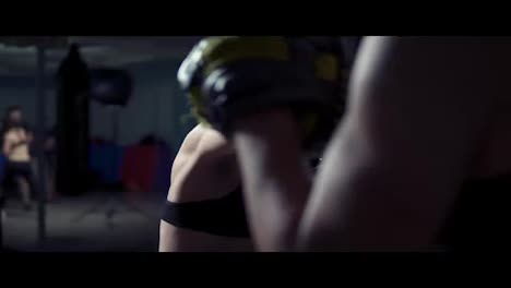 Young-attractive-woman-in-boxing-gloves-training-with-her-couch-in-a-boxing-club.-Slow-motion-shot