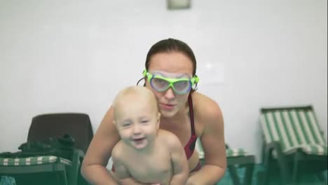 Cute-blonde-toddler-is-diving-under-the-water-together-with-his-mother-in-special-protective-glasses-in-the-swimming-pool.-His