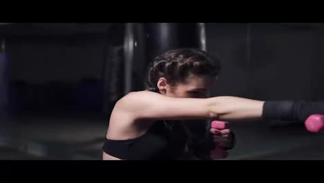 Young-woman-training-with-her-hands-wrapped-in-boxing-tapes-holding-dumbbells.-Slow-Motion-shot