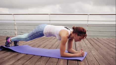 Young-woman-training-on-the-beach-in-front-of-the-ocean.-Morning-gymnastic.-Elbow-and-hand-plank-exercise.-Healthy-active