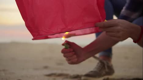 Close-Up-view-of-hands-lightning-before-launching-red-paper-lantern.-Female-hands-holding-lantern-with-fire-before-to-let-it-fly