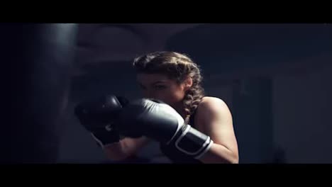 Beautiful-young-tanned-woman-punching-bag-in-fitness-studio.-Boxing-in-Slow-Motion