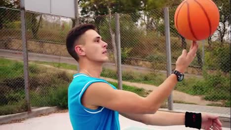 Portrait-of-a-young-serious-looking-basketball-player-spinning-a-basketball-on-the-street-playing-field.-Slow-Motion-shot