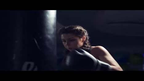 Beautiful-young-tanned-woman-punching-bag-in-fitness-studio.-Boxing-in-Slow-Motion