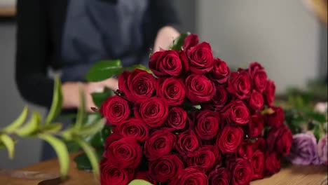 Perfekter-Strauß-Roter-Rosen-Auf-Dem-Tisch.-Nahaufnahme-Der-Hände-Einer-Floristin,-Die-Einen-Modernen-Blumenstrauß-In-Wunderschönem-Rot-Arrangiert