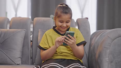 Happy-Indian-kid-girl-scrolling-and-using-phone