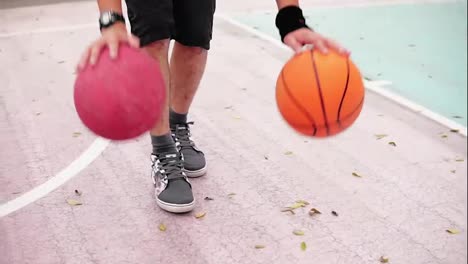 Unrecognizable-man-practicing-basketball-on-the-street-court.-He-is-playing-with-two-balls-simultaneously.-Slow-Motion-shot