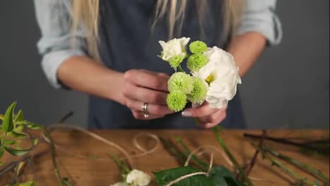 Close-Up-view-of-hands-of-professional-blonde-female-floral-artist-arranging-beautiful-bouquet-at-flower-shot.-Floristry