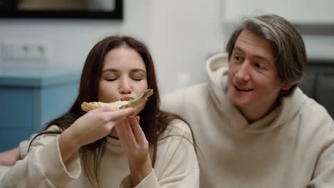 Young-woman-eats-pizza-and-offers-bite-to-boyfriend,-they-feeling-so-happy