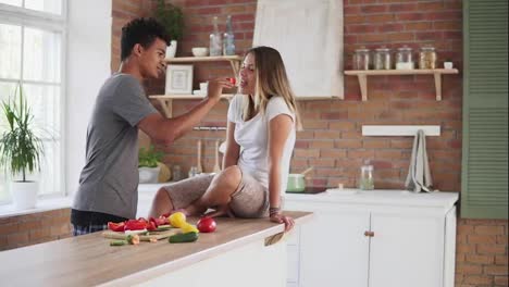 Slow-Motion-shot-of-attractive-multi-ethnic-couple-chatting-in-the-kitchen-early-in-the-morning.-Handsome-man-feeding-his-wife