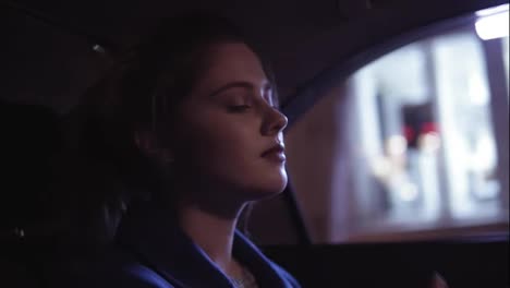 Attractive-young-woman-with-her-eyes-closed-is-riding-in-taxi-sitting-on-the-backseat-and-listening-to-the-music,-moving-her