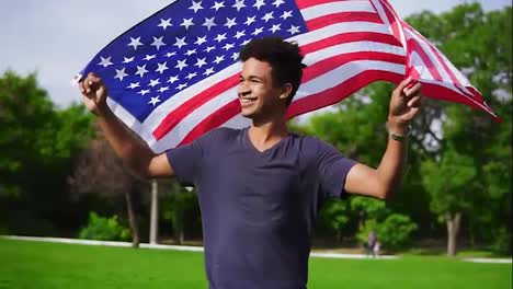 Attractive-african-american-man-holding-American-flag-in-his-hands-on-the-back-walking-in-the-green-field-and-smiling-proudly