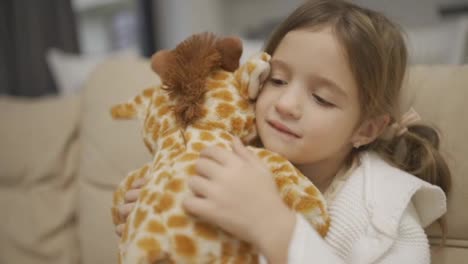 A-little-girl-hugs-her-favorite-toy,-soft-giraffe