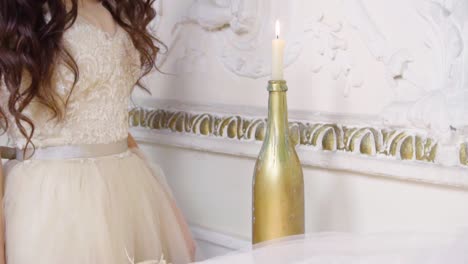 Young-brunette-woman-in-long-evening-dress-plays-with-candle