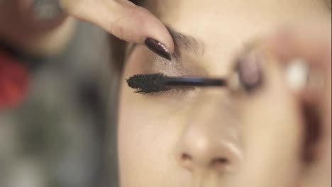 Close-Up-view-of-professional-makeup-artist-applying-mascara-on-the-model's-eyelashes.-Work-in-beauty-fashion-industry.-Backstage