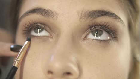 Close-Up-view-of-professional-makeup-artist-hands-using-makeup-brush-to-apply-eye-shadows.-Slow-Motion-shot