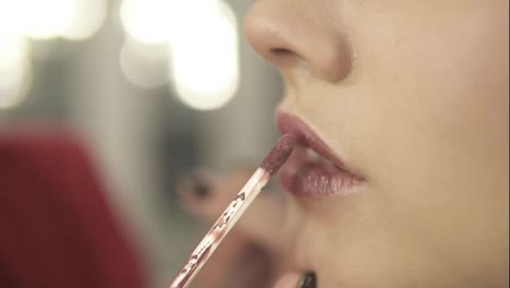 Close-Up-view-of-a-professional-makeup-artist-applying-lipstick-on-model's-lips-working-in-beauty-fashion-industry.-Close-Up-view