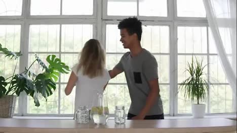 Attractive-african-man-embracing-his-caucasian-girlfriend-while-dancing-in-the-kitchen.-multi-ethnic-couple-in-pajamas-having