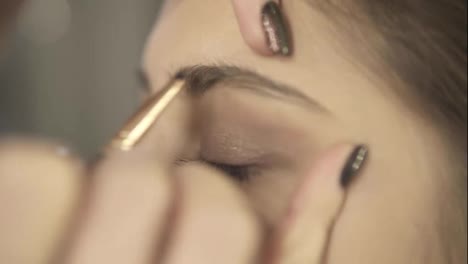 Eyebrows-care-during-professional-makeup:-Close-Up-of-a-young-woman-getting-her-brows-shaped-with-brow-brush-and-shadows