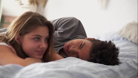 Close-Up-view-of-happy-multiracial-couple-lying-in-bed-and-talking.-Attractive-young-man-and-woman-in-love.-Romantic-concept