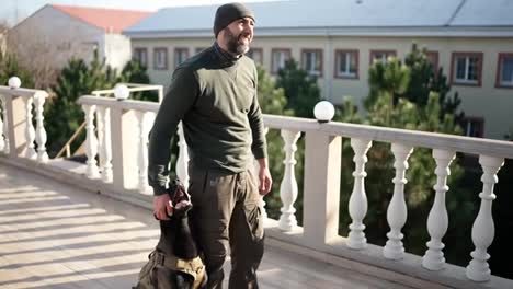 A-man-stands-on-terrace-with-service-dog-in-military-protective-collar