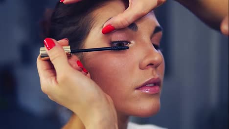 Professional-makeup-artist-applying-mascara-on-the-model's-eye.-Work-in-beauty-fashion-industry.-Backstage-professional-make-up