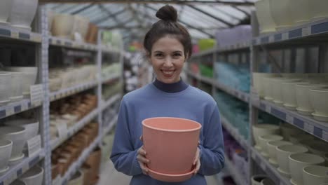 Portrait-of-a-female-customer-chose-clay-flower-pot-for-home-garden-standing-in-floral-department