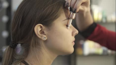 Makeup-artist-applies-concealer-on-the-face-of-a-young-girl.-Base-for-perfect-makeup.-Slow-Motion-shot