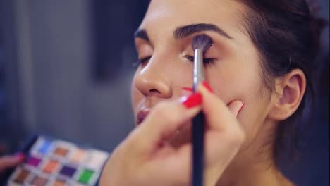 Professional-make-up-artist-applying-eyeshadow-to-model-eye-using-special-brush.-Beauty,-makeup-and-fashion-concept.-Slow-Motion