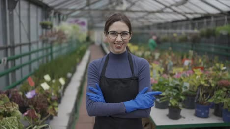 Female-worker-florist-crossing-her-arms-standing-on-the-greenhouse-background