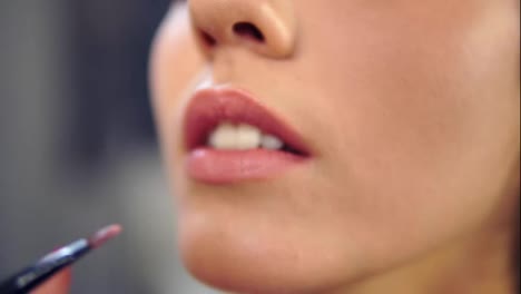 Close-Up-view-of-a-professional-makeup-artist-applying-lipstick-on-model's-lips-working-in-beauty-fashion-industry.-Close-Up-view