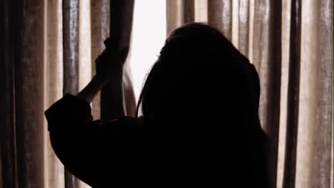 Slow-Motion-backside-footage-of-a-female-silhouette-opening-up-the-curtains-and-letting-the-light-into-the-room