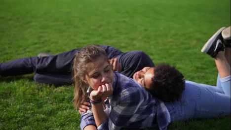 Handsome-african-guy-lying-on-the-back-of-his-caucasian-girlfriend-on-the-green-field-and-talking.-multi-ethnic-couple-enjoying