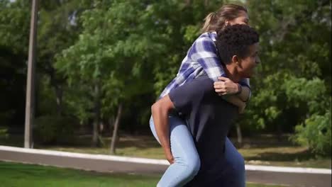 Romantic-date-of-a-happy-multi-ethnic-couple:-handsome-african-guy-piggybacking-his-caucasian-happy-girlfriend-and-spinning-her