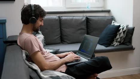 Caucasian-man-in-headphones-typing-on-laptop-at-home,-social-media-communication