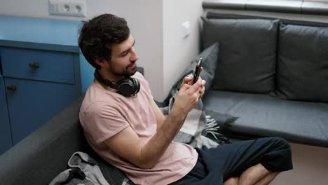 Man-on-the-sofa-scrolling-on-smartphone-at-home