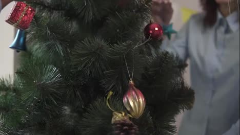 Close-Up-view-of-a-little-artificial-Christmas-tree-decorated-by-happy-smiling-office-workers.-Christmas-and-New-Year-celebration
