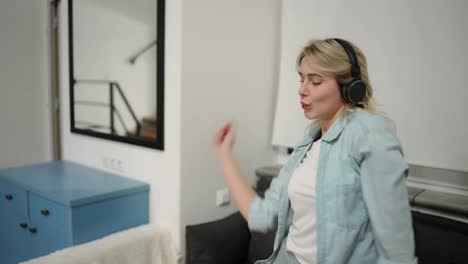 Happy-young-woman-dancing-at-home-having-fun-listening-to-music-wearing-headphones