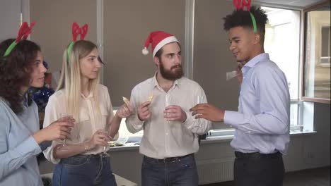 Young-attractive-african-man-telling-his-story-during-corporate-Christmas-party-in-the-office.-Multiracial-group-of-happy-office