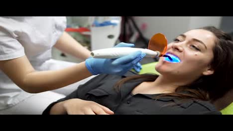 Young-female-patient-with-open-mouth-receiving-dental-filling-drying-procedure