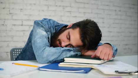 Close-Up-view-of-young-office-worker-or-student-sleeping-at-the-table-with-notebooks-on-the-table