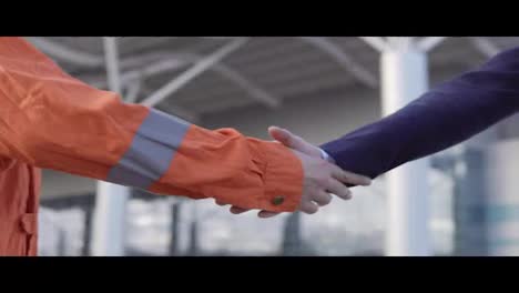 Professional-worker-in-orange-uniform-shaking-hands-with-businessman-in-a-suit.-Close-Up-view