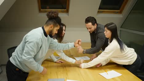 Team-of-entrepreneurs-stacking-fists-to-a-tower-in-conference-room