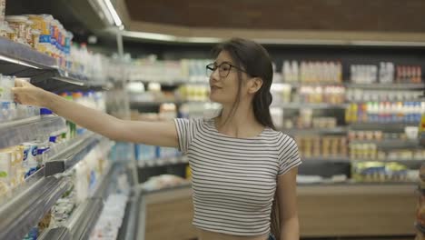 and-Asian-girl-visitor-chooses-a-products.-Happy-shot-visitor.-Choice-of-products-in-the-store