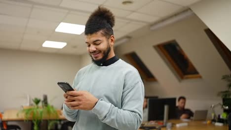 Successful-mixed-race-businessman-smiling-while-reading-message-on-cell-phone