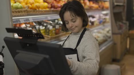Arbeiter-Mit-Down-Syndrom-Nutzt-Ein-Digitales-Tablet-In-Der-Frischwarenabteilung-Eines-Lebensmittelladens
