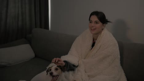 Erwachsene-Frau-Mit-Decke-Bedeckt,-Die-Zu-Hause-Einen-Film-Mit-Dem-Hund-Jack-Russell-Terrier-Ansieht