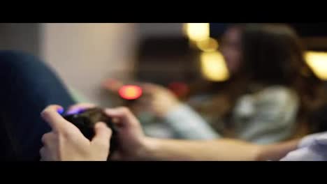 Young-couple-playing-video-game-at-home.-Man-explaining-how-to-play-and-use-the-game-controller.-Wireless-game-controller