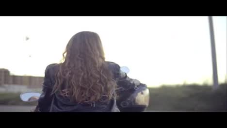 Back-view-of-a-female-biker-with-long-hair-sitting-on-the-motorcycle-seat.-Close-up-of-young-curly-woman-on-the-chopper